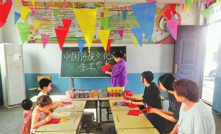 齐小丽教留守儿童学剪纸.