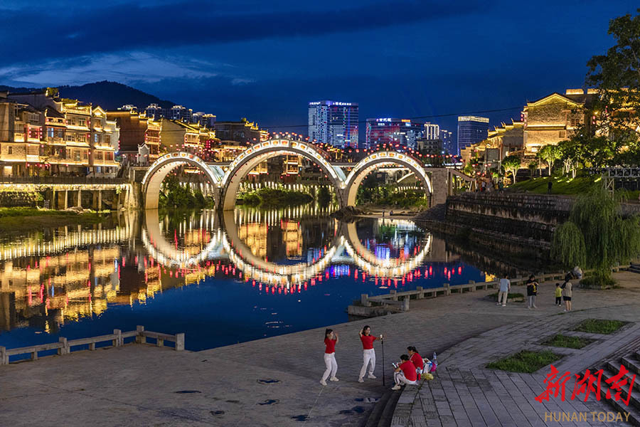 6月10日傍晚,吉首市乾州古城华灯初上,古朴的建筑倒映在万溶江中如梦