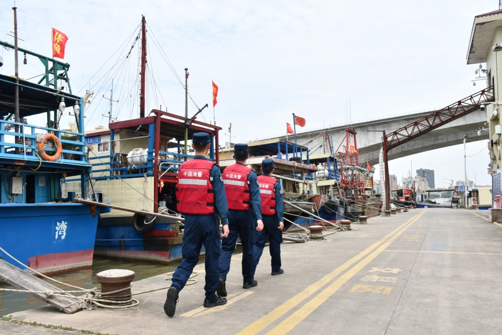 广东海警执法员落实防风防汛工作,对辖区沿海码头设施,建筑物和船只
