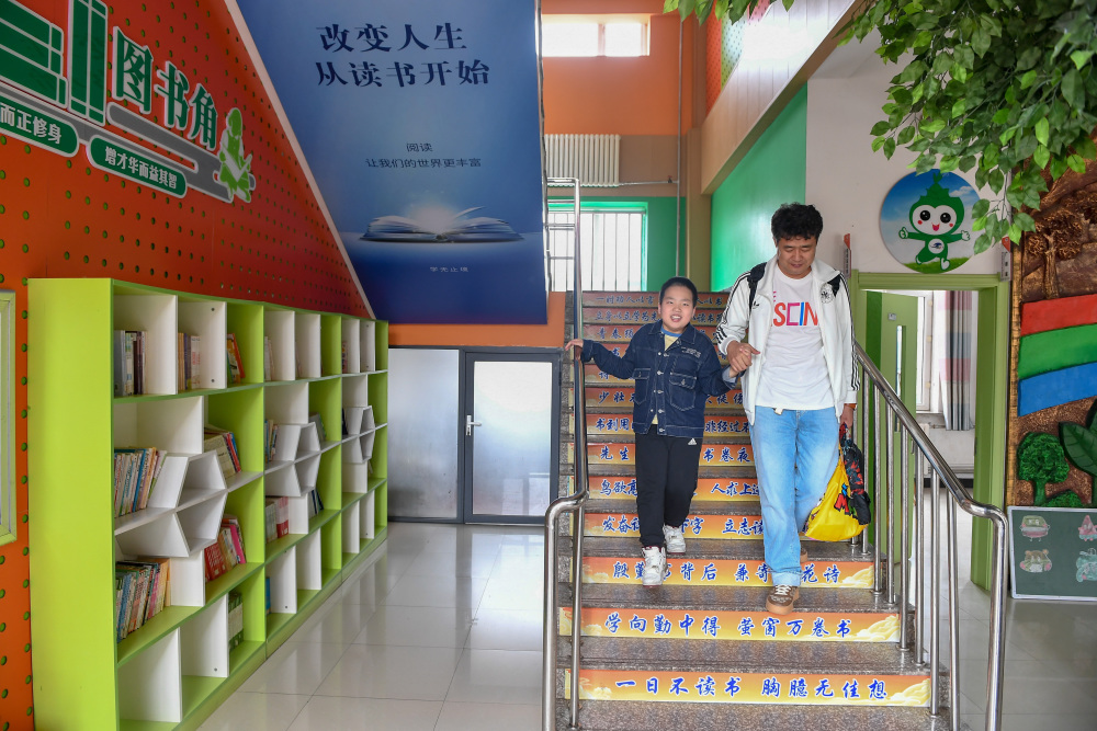 5月30日,在长春净月潭实验小学,父亲扶着爱马下楼.