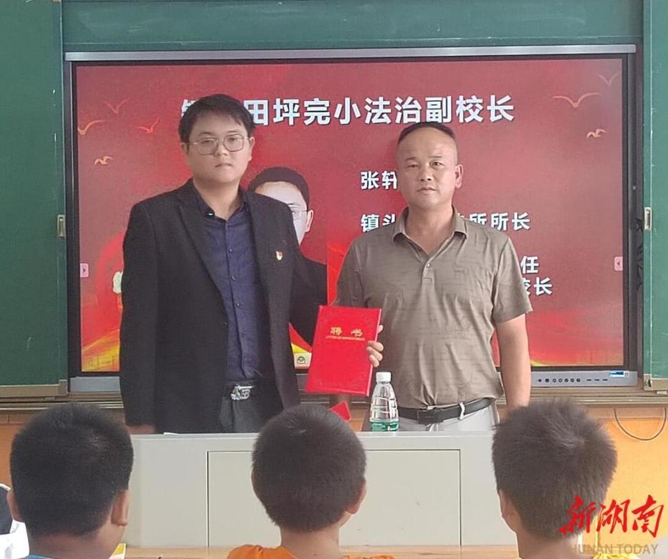 校长黄伟明首先为张轩颁发聘书,聘任为田坪小学法制副校长