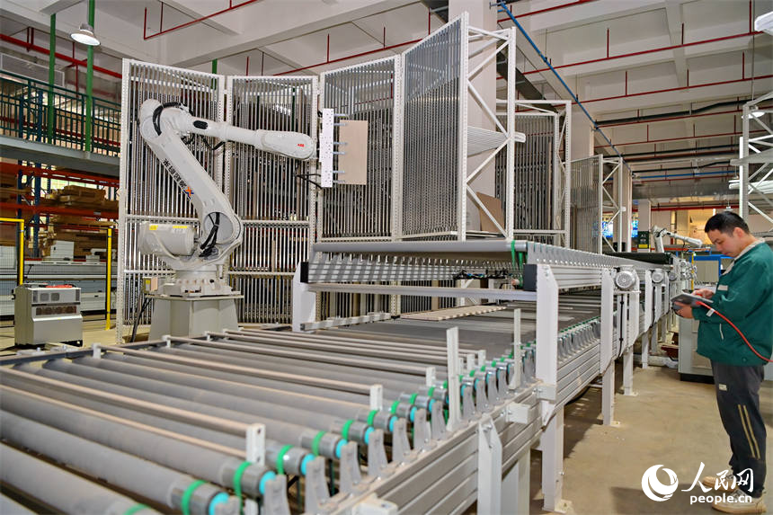 赣州市南康区的一家定制家具智能制造企业车间里,工人在生产线上操作