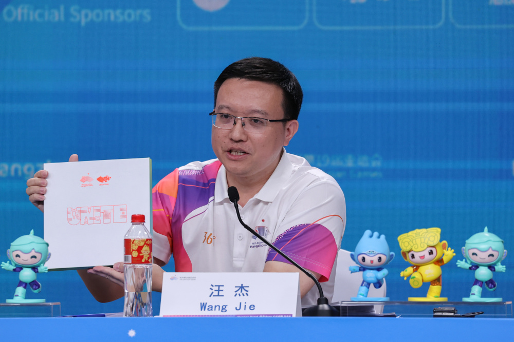 志愿者部部长汪杰在发布会上展示杭州亚运会志愿者专属纪念品"小青盒"