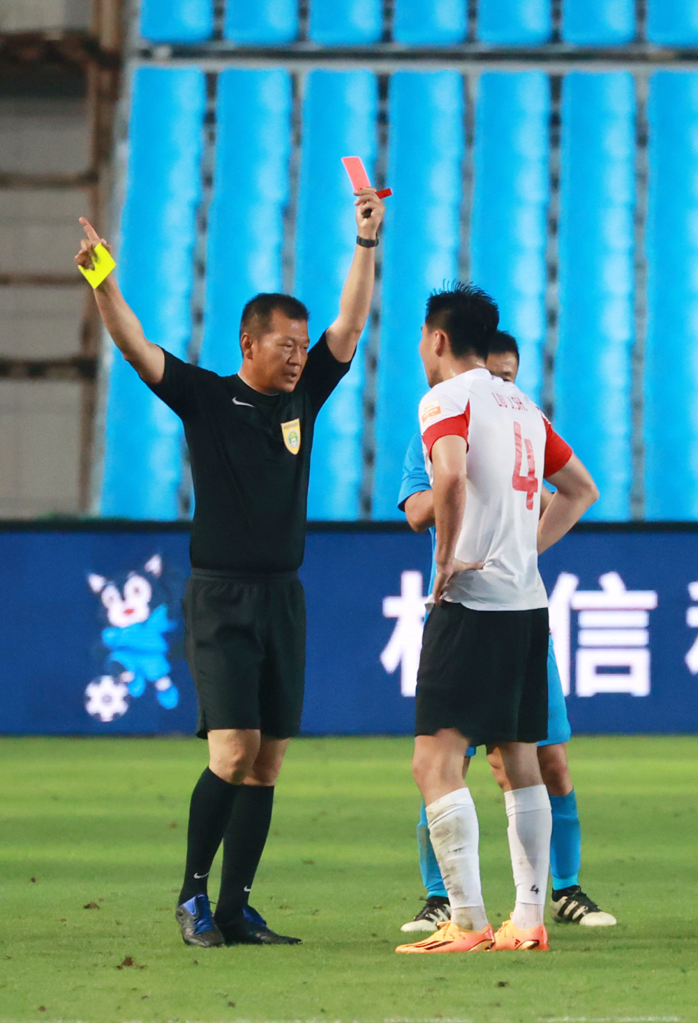 6月4日,主裁判王哲(左)向青岛海牛队球员刘军帅出示红牌.