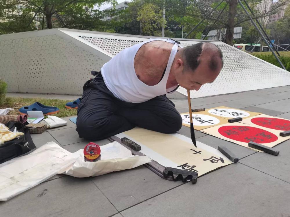 无臂父亲口衔毛笔书写励志人生_腾讯新闻