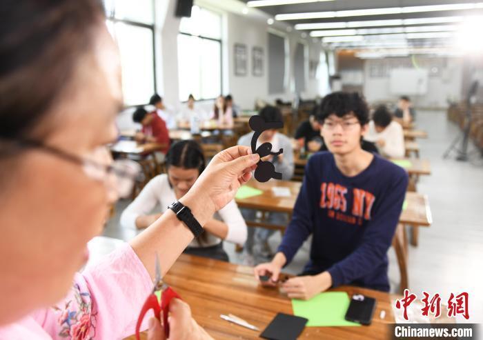 中新网记者 周毅 摄图为老师为留学生讲解剪中国大熊猫图案的方法.