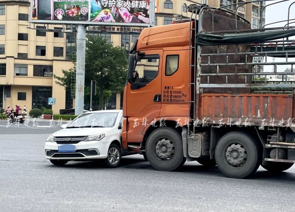 小轿车左侧车体和一辆直停在第二车道前方的大货车车头紧紧挨在一起