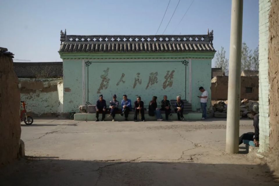 4月17日,山西代县,一位年轻记者在坐满老人的照壁下采访.
