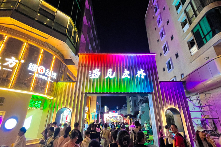 浅灰色的铝板门头呈波浪流线形,彩色的灯光效应熠熠生辉,与两侧建筑的