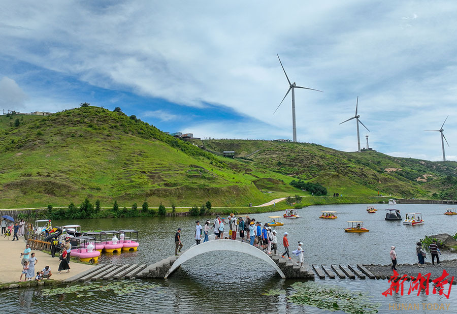 7月13日,游客在郴州市北湖区仰天湖大草原的湖边游览.