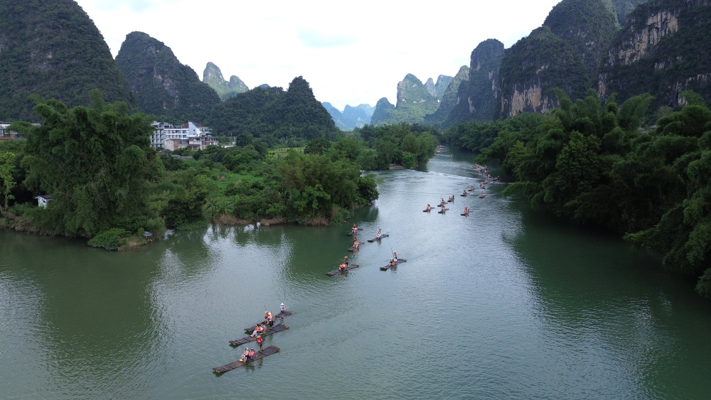 2024年7月9日,游人在广西桂林市阳朔县遇龙河乘坐竹筏漂流观景