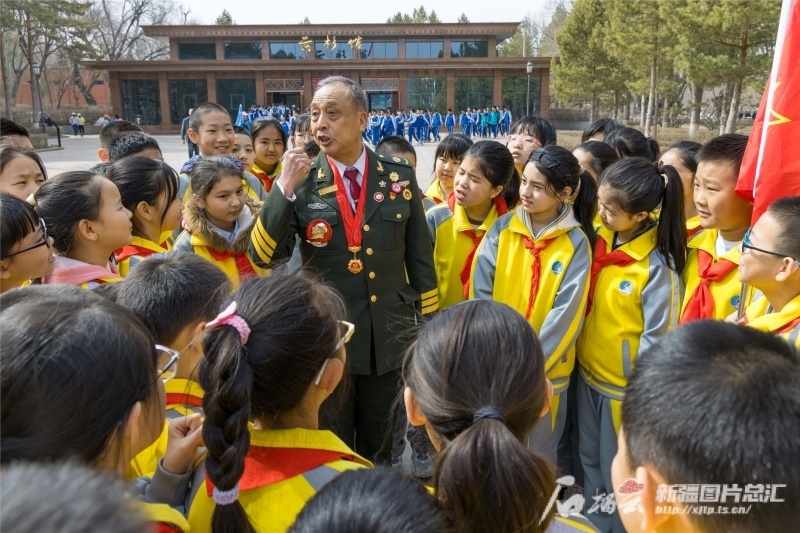 3月29日,乌鲁木齐市第62小学学生在听79岁老兵梁开元讲革命故事.