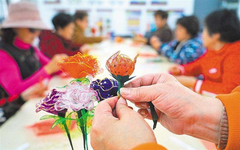 3月26日,非遗传承人龚智瑜(中)在上海市中山学校给同学讲授灯彩制作