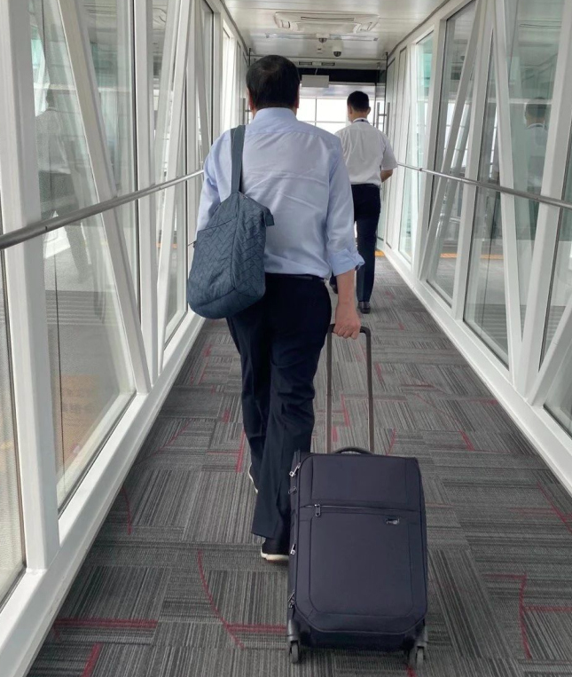 这位永远在业务一线的商界传奇,拉着行李箱行走的背影照片,恰如那个三