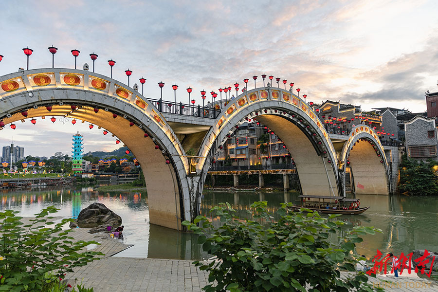6月10日傍晚,吉首市乾州古城华灯初上,古朴的建筑倒映在万溶江中如梦