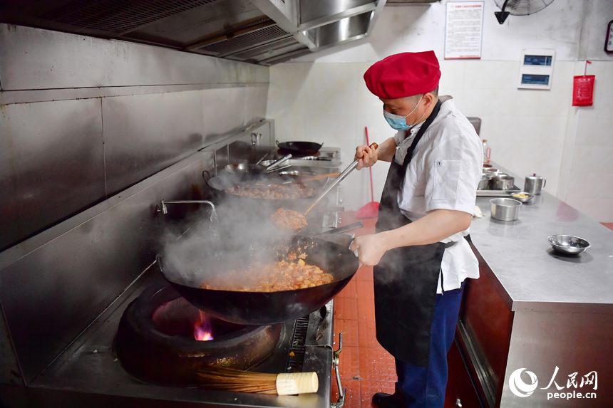 红谷滩区九龙馨苑社区的幸福食堂后厨,工作人员将蒸好的米饭端往打菜