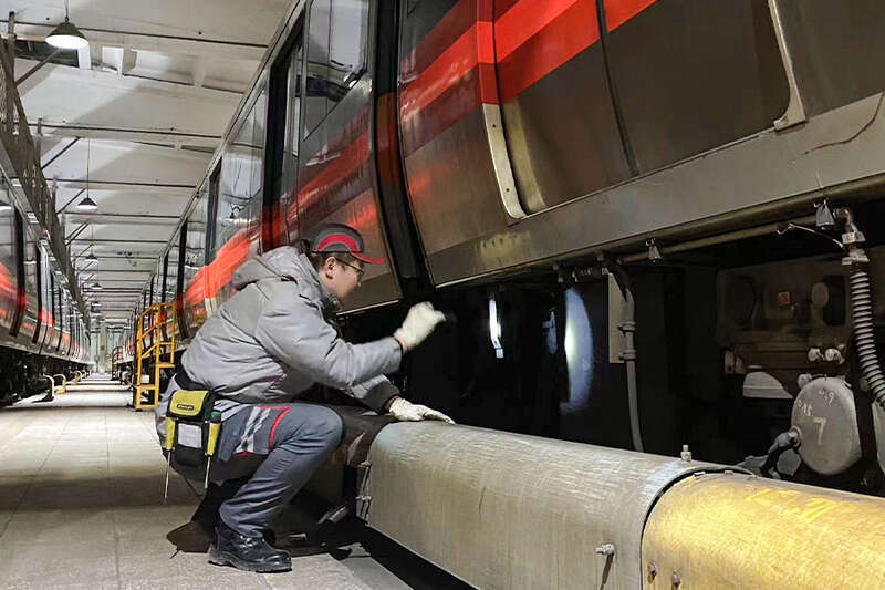 凌晨的停车列检库里,顶部的灯光将并列停放着的地铁电动客车照得锃亮