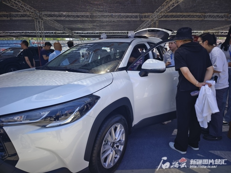 在首届乌鲁木齐汽车集市暨第14届新疆端午国际车展上,消费者正在看车.