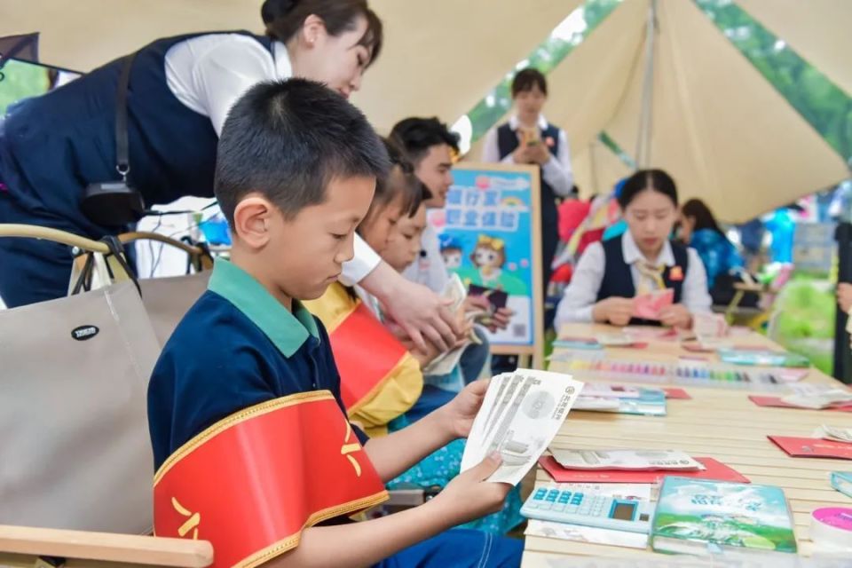 北京银行工作人员为小小银行家们介绍银行机具.