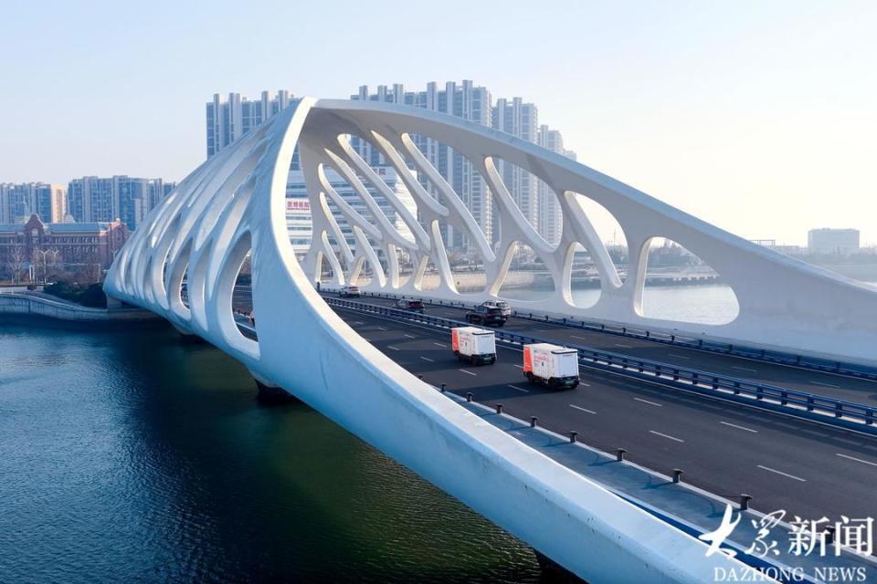 12月6日，两辆无人配送车从青岛西海岸新区珊瑚贝桥上经过。“截至12月6日，公司无人配送车已在山东省16个地市实现全覆盖，在青岛部署超1200台，成为国内乃至全球无人配送车部署最密集的城市之一。”新石器慧通（北京）科技有限公司青岛事务经理王靖鑫介绍。目前，这些车辆主要集中于城阳区、即墨区和青岛西海岸新区，广泛应用于批发市场、连锁商超、社区便利店等场景，为青岛智慧城市注入高效便捷的物流新动能。预计到