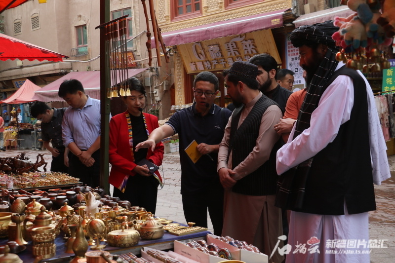 图为代表团在喀什古城街头听讲解员介绍特色手工艺品