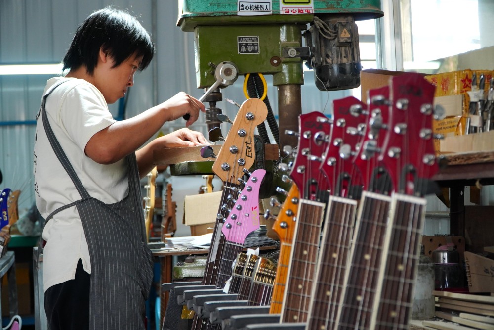 省昌乐县鄌郚镇的一家乐器生产企业,一名工作人员在生产加工电吉他