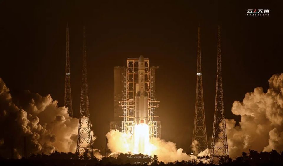 长五火箭点火起飞,尾焰发出的光一瞬间照亮了海滩上的人群.