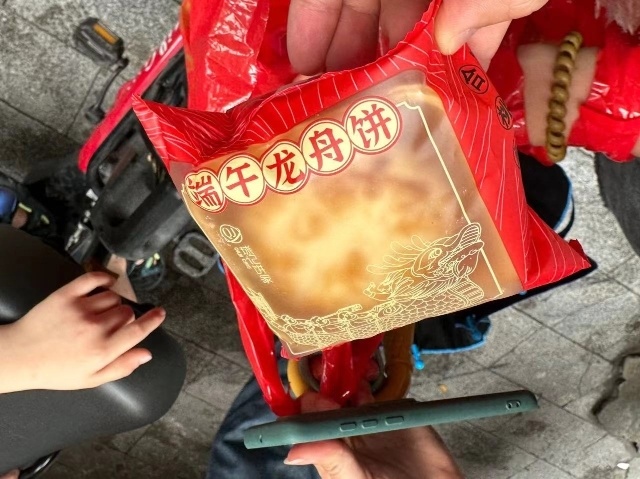 一位村民下船后开心地向记者展示了龙船饼:"吃饼就是图个好意头,希望