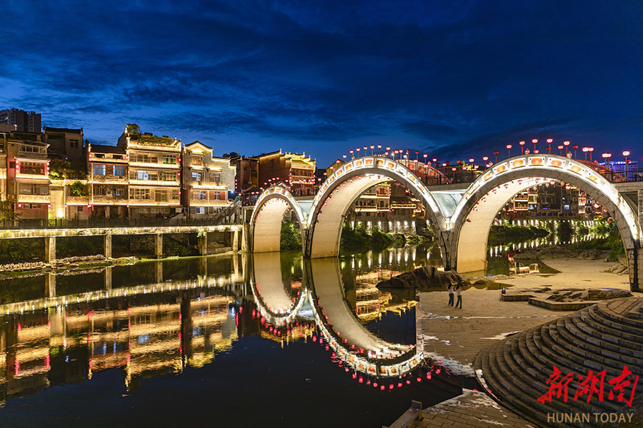 6月10日傍晚,吉首市乾州古城华灯初上,古朴的建筑倒映在万溶江中如梦