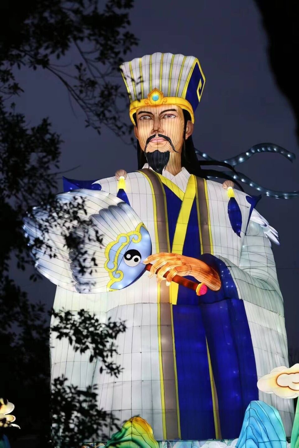 身披鹤氅的卧龙先生诸葛孔明,端坐于高台之上,淡定抚琴,羽扇在他身后